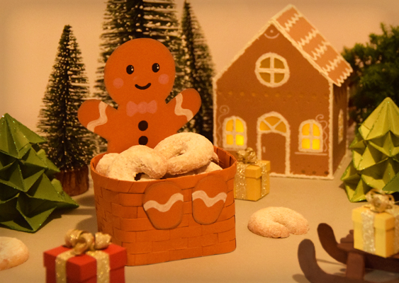 Lebkuchenhaus mit leuchtenden Transparentfenstern, Lebkuchenmann mit Korb voller Vanillekipferl und winterlicher Zauberwald – Papierkunst von Veronika Helga Vetter, Webkünstlerin seit 2012 Die Szene liegt in warmem, sanft gedämpftem Licht, als hätte jemand die Stille eines frühen Winterabends eingefangen. Alles wirkt von einem goldgelblichen Schimmer überzogen – nicht grell, sondern leise leuchtend, beinahe so, als sei der Raum selbst aus Honiglicht gewebt. Im Hintergrund thront ein liebevoll gearbeitetes Lebkuchenhaus aus Papier. Seine Fassaden bestehen aus feinen Kartonflächen, die Fenster sind mit transluzentem Transparentpapier hinterlegt, weiß gerahmt, fast wie Zuckerglas. Dahinter glimmen zwei elektrische Teelichter, deren warmer Schein das Haus von innen heraus zum Strahlen bringt. Durch die gedimmte Studiobeleuchtung treten diese Lichtpunkte umso stärker hervor und verleihen dem gesamten Arrangement eine märchenhafte Tiefe. Im Vordergrund, leicht versetzt, steht der vertraute Lebkuchenmann mit seinem siennafarbenen Flechtkorb – das Herzstück der Komposition. Sein Korb ist bis zum Rand gefüllt mit frisch gebackenen Vanillekipferln, die Veronika Helga Vetter selbst hergestellt hat. Die Kipferl liegen locker geschichtet, hellgolden, zart bemehlt, so realistisch, dass man den Duft förmlich zu riechen meint. Das warme Braun des Korbes harmoniert perfekt mit dem cremigen Ton des Gebäcks, wodurch das Ensemble ruhig und geerdet wirkt. Hinter und um die Hauptfiguren herum breitet sich ein kleiner weihnachtlicher Zauberwald aus. Zwischen dem Lebkuchenhaus und dem Korbmann stehen verschiedene Christbäume – einige gefertigt aus weichem Chenilledraht, die von Kunstschnee überzogen in kleinen braunen Töpfchen wurzeln. Dazwischen funkeln Origami-Bäumchen aus grünem Papier, die mit winzigen Glitzerpartikeln bestäubt wurden. Dieses Zusammenspiel aus Textur, Glanz und Form schafft ein harmonisches Winterbild zwischen Handwerk und Fantasie. In den freien Flächen des Arrangements schimmern kleine Geschenkverpackungen, diesmal in Vanille- und Rottönen, mit goldenen Schleifen, wie zufällig, aber doch mit Blick für Balance arrangiert. Ganz vorne rechts ist ein Papierschlitten zu sehen, halb im Anschnitt, auf dessen Sitzfläche eines der Päckchen ruht – ein stilles Symbol für Bewegung und Erwartung. Diese Komposition ist mehr als nur Dekoration; sie erzählt von Licht, Handwerk und Geduld. Das Arrangement stammt von Veronika Helga Vetter, österreichische Papier- und Webkünstlerin seit 2012, deren Werke den Zauber von Weihnachtsduft und Bastelkunst in eine feine, poetische Bildsprache übersetzen. Weihnachten auf GWS2.de